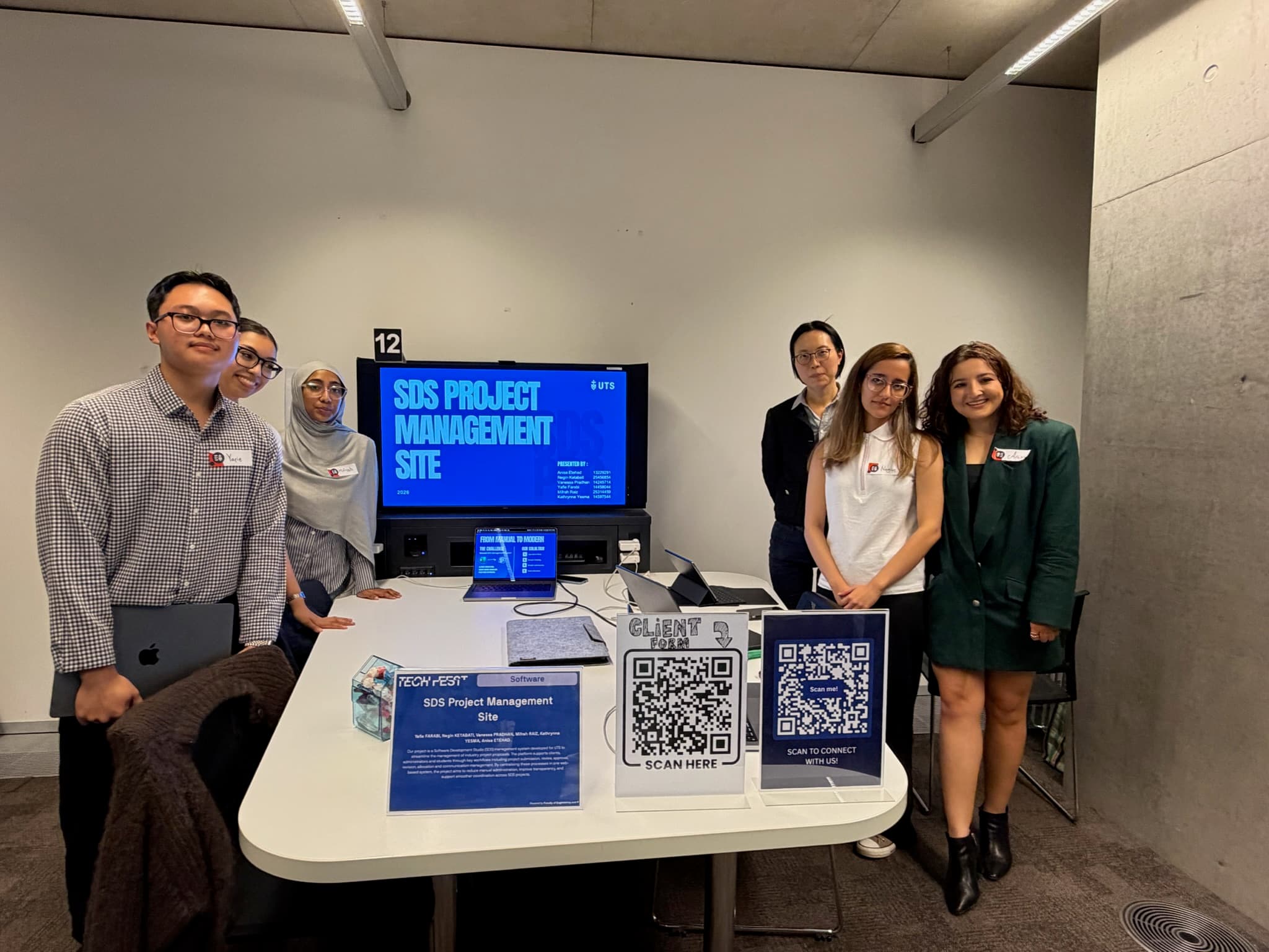 SDS Project Management Site booth team standing with the client-facing Tech Fest setup